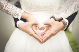 Le mari entrelaçant sa femme par derrière. Les deux forment un coeur avec leurs mains - noces de coton
